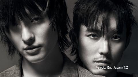 Woods and Justin H. Min pose in moody lighting, teasing their mystery short film “Slide Strum Mute” ahead of its February 26 release.